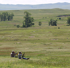 large grassy plain, with hunters 
