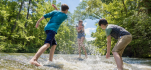 Three kids play in the water while hiking in Kisatchie National Forest.