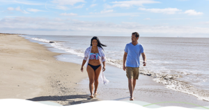 A man and woman walking along the shore Holly Beach in Louisiana.