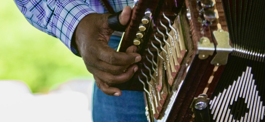 Close up shot of hand playing accordion.