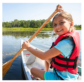 Young child rowing a canoe on a lake