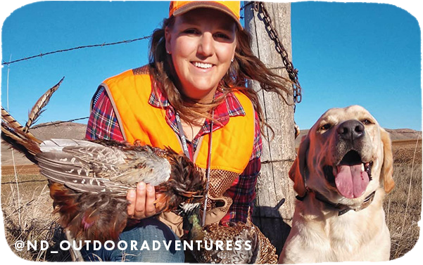 Woman holding a hunted bird with a dog next to her