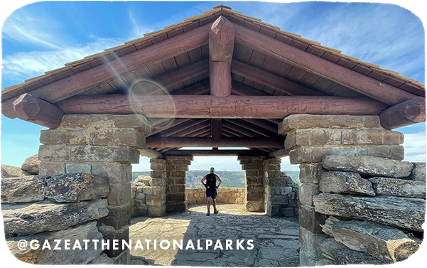Person standing under a large wood and stone shelter at a national park