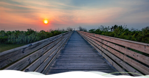 A boardwalk in Grand Isle, Louisiana leads to a sunset.