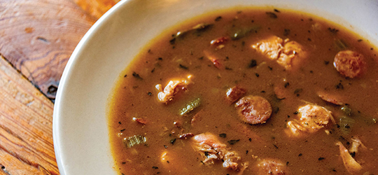 A close-up of a bowl of chicken and sausage gumbo, featuring Andouille sausage.