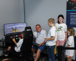 A group of kids waiting to use a simulator machine