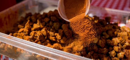 A tray of fresh cracklin being seasoned.