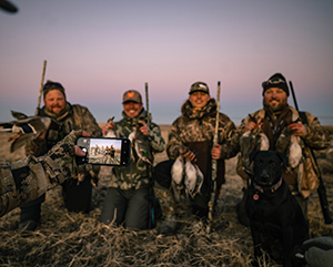 4 men wearing camo hunting outfits taking a picture of their duck hunt