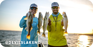 Two smiling men holding up two fish each while on the water with text overlay that reads @DevilsLakeND