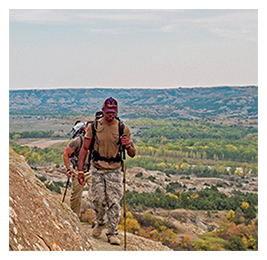 Man hiking on a rocky shelf holding a pole