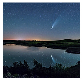 A night sky with stars and a shooting star over a reflective body of water