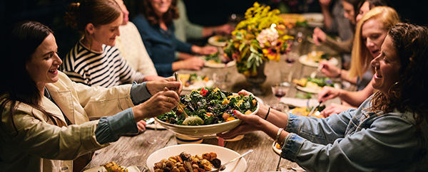 Friends gathered around a wooden table sharing a meal together.