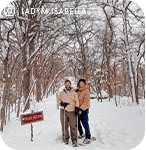 Two people standing in a snowy forest on cross-country skis