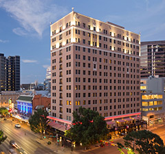 An exterior view at dusk of the multistory Stephen F. Austin Royal Sonesta Hotel in Austin, Texas
