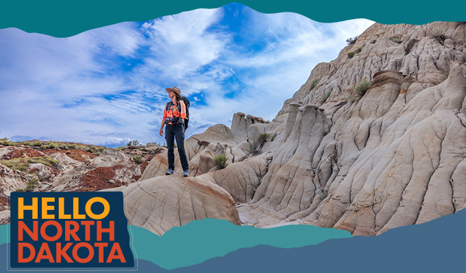 A woman standing on rock formations looking into the distance, with overlay text that reads: Hello North Dakota