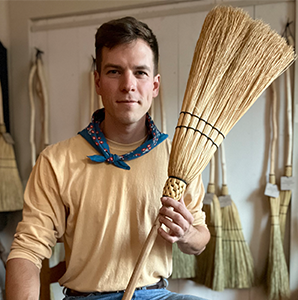 Man sitting with a homemade broom. 