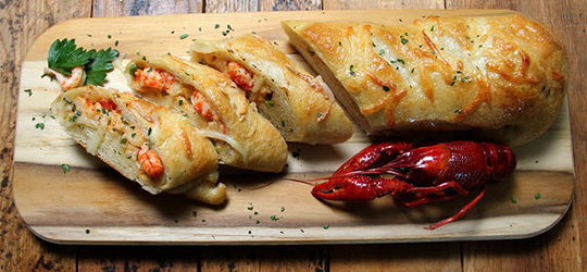 Sliced crawfish bread rests on a a cutting board.