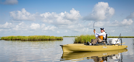 A fisherman casts a line from a kayak.