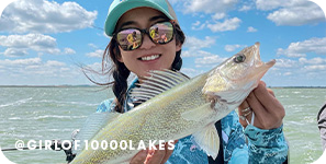 Girl holding a fish on a sunny day on a lake, with overlay text that reads: @girlof10000lakes
