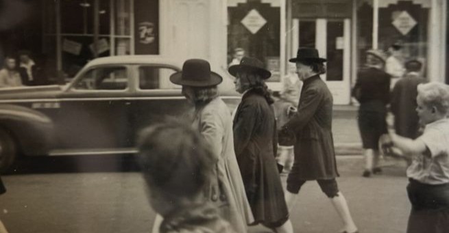 A black and white photo from a past Day in Old New Castle shows people parading down the street.	