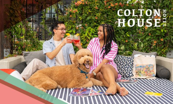 Two people sitting on a lounger with a dog.
