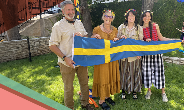 Four smiling people holding a yellow and blue Swedish banner