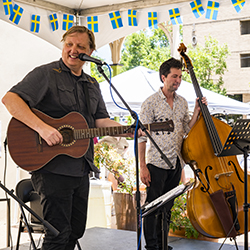 Two people playing musical instrument behind a micrphone.