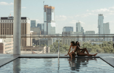 Two women sit on the edge of the rooftop pool at The Otis Hotel in Austin, Texas