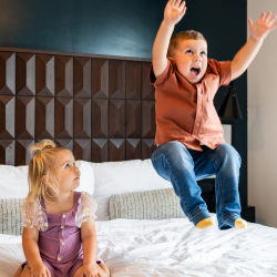 two kids jumping on a hotel bed