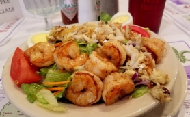 A salad topped with a heaping of grilled shrimp.