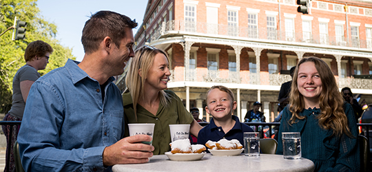 A family of four enjoys beignets at Cafe Du Monde in New Orleans.
