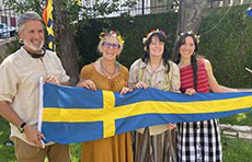 Four people hold a Swedish flag at the Midsummer Festival in Austin, Texas