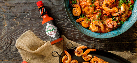 A table with a shrimp dish featuring TABASCO® hot sauce.