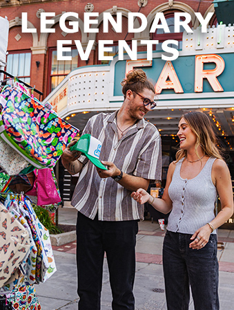 A man and a woman looking at a hat for sale outside of a theater, with overlay text that reads: Legendary Events