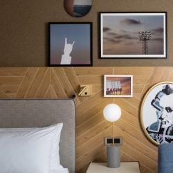 Decorative items on a wall above a bed and end table inside an AustinPlace room in Austin, Texas
