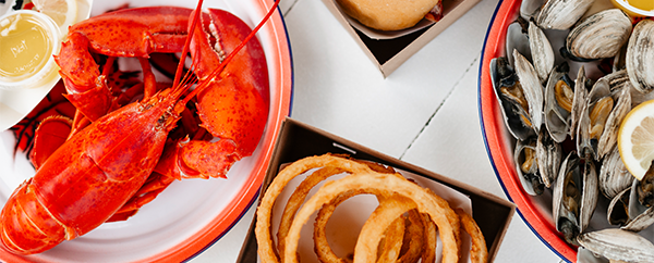 White picnic table with lobster, clams and onion rings