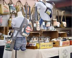 Mannequins wearing bags while surrounded by handbags and other items in a shop