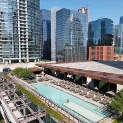 Aerial view of the outdoor swimming pool at the JW Marriott Austin with the city skyline behind it