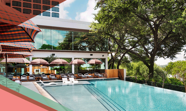 A view of the main pool surrounded by lounge chairs under umbrellas at The LINE Austin hotel