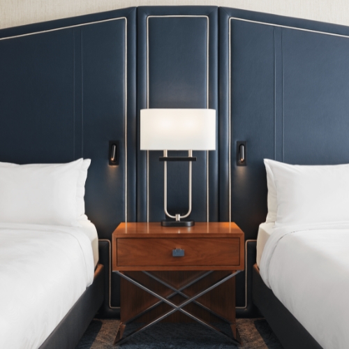 A view inside a contemporary guest room with two beds and a night table at JW Marriott Austin 