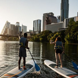Two people use paddleboards on Lady Bird Lake near The LINE Austin hotel