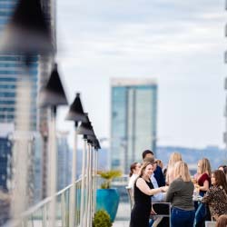 People stand around a high-top table and socialize at the Azul Rooftop at The Westin Austin Downtown