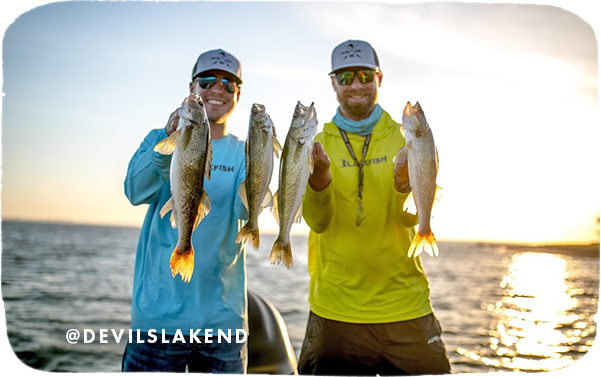 Two men standing on a boat holding caught fish with water and sunset in the background, with overlay text that reads: @devilslakend