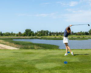 Woman swinging a golf club on a golf course