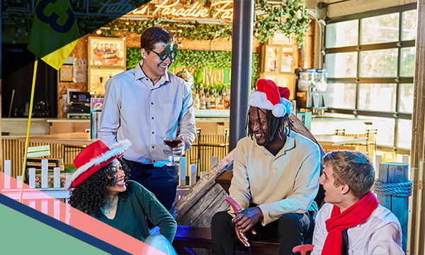 People wearing red Christmas hats and scarfs socialize inside Holey Moley