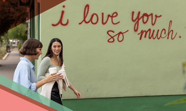 Two women walk by the i love you so much mural in Austin