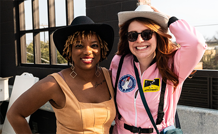 Two women pose in cowboy hats on the rooftop of Home2 Suites East Austin