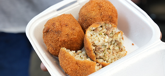 A patron holds a plate of crispy boudin balls.