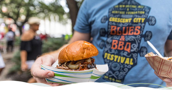 Person holding a barbecue sandwich at the Crescent City Blues & BBQ Festival.