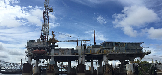 Offshore oil rig with cranes and equipment against a partly cloudy sky.